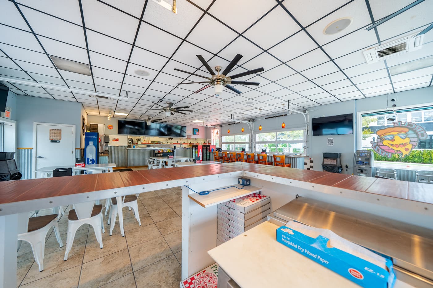 The service counter and kitchen pass, with stools along the front.